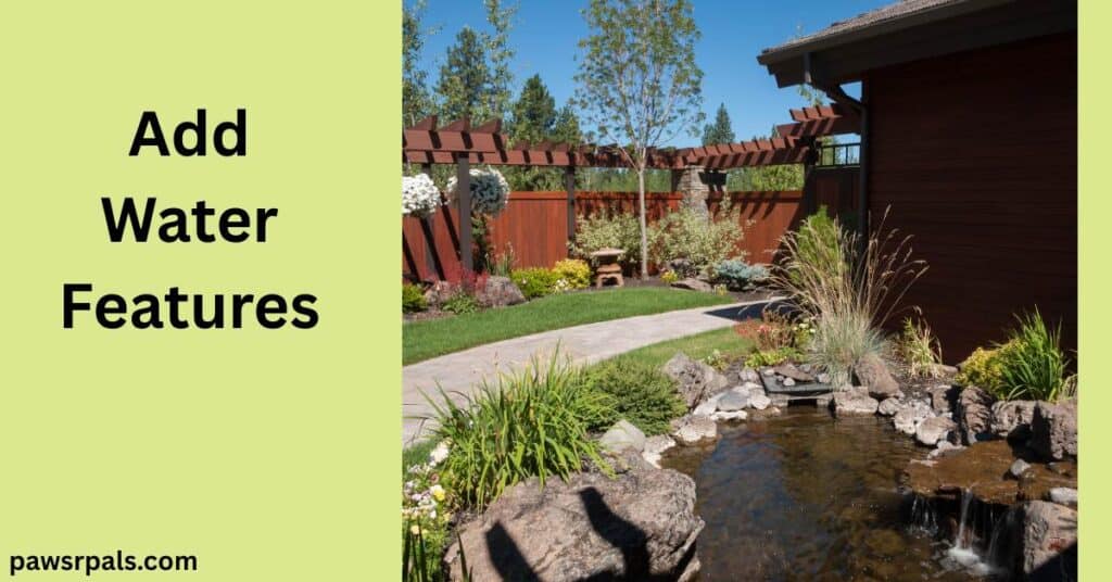Add Water Features. Image on the right, pond surrounded by rocks with greenery around the edge, pale path separating the grass and dark brown fence in the background